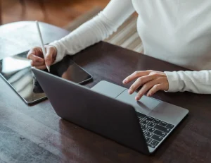 Persona teletrabajando con laptop y tablet mientras gestiona la elección de su comuna para el domicilio tributario en Chile.